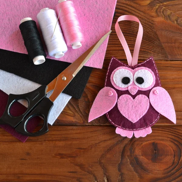 Felt owl toy. Kids DIY crafts. Sheets of colored felt, scissors, thread, needle, wooden table