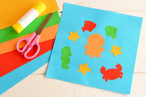 Paper applique with sea animals and fishes. Art lesson in kindergarten. Paper sea animals - octopus, fish, starfish, seahorse, crab. Kids crafts. Sheets of colored paper, scissors, glue