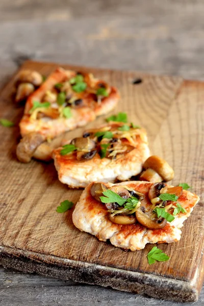 Roasted sliced Turkey fillet with cheese, agaricus and parsley on a cutting board and an old wooden table. Tasty cooked Turkey meat. Lunch, dinner, picnic menu. Closeup