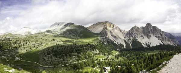 Panoramic view to alpine huts in green valleys surrounded by the mountains and snow picks