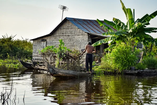 Floating village house with a man on Tonle Sap Lake, Cambodia