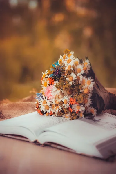 Beautiful wild summer flowers bouquet on the open book in retro style