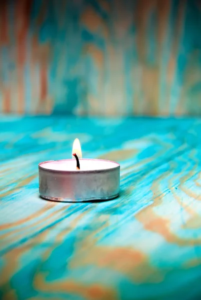 Tea light candle on a blue wooden textured background