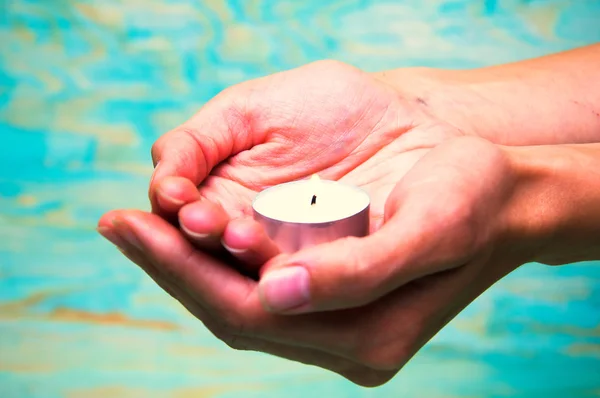 Woman\'s hands holding a tea light candle