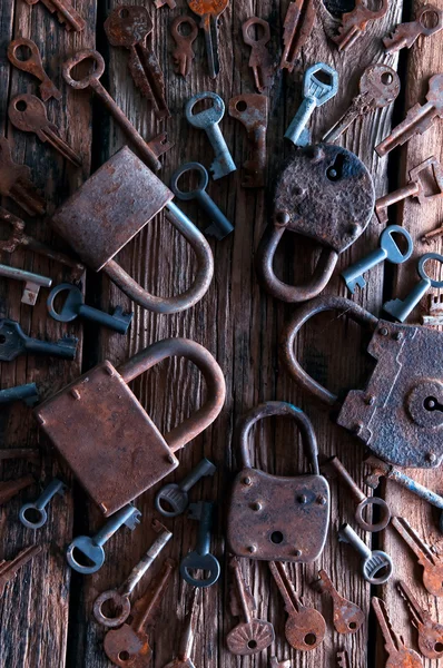 Old rusty padlock and keys on wooden background