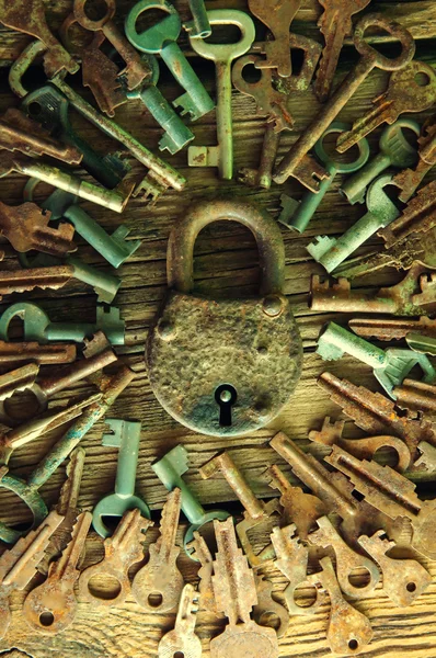 Old rusty padlock and keys on wooden background