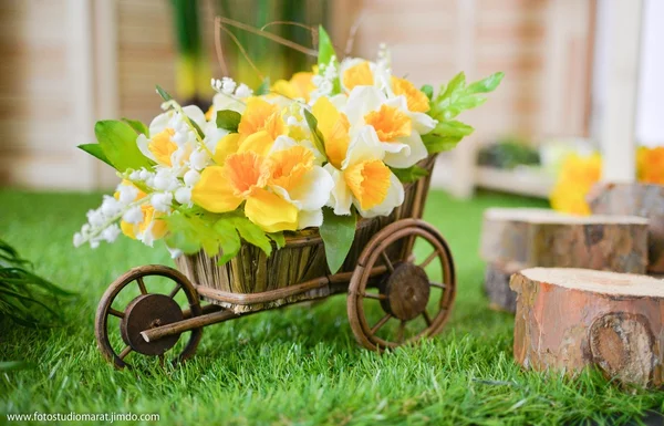 Decorative three-wheeled cart with white decorative flowers on a green grass decor