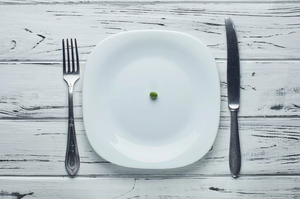One small green pea on the empty plate.