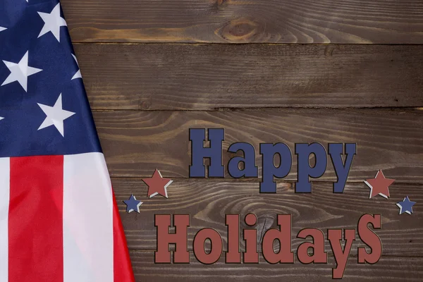 Happy holidays. American flag, text on a wooden background. view from the top, space for advertising.