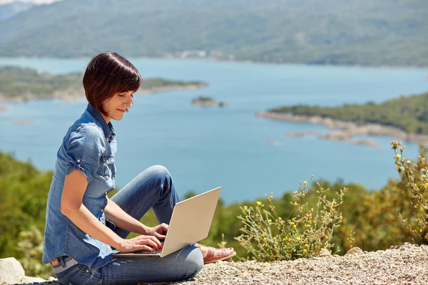 Beautiful young freelancer woman using laptop sitting on the lak