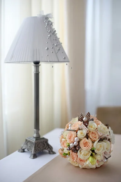 Bouquet of  pink and white roses on the table near the lamp with