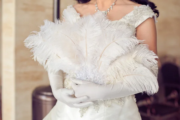 Fan feather in hands of the bride