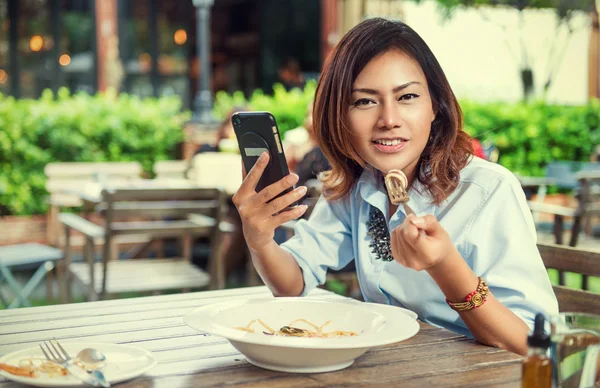 Asian women are happy when eating and playing mobile games