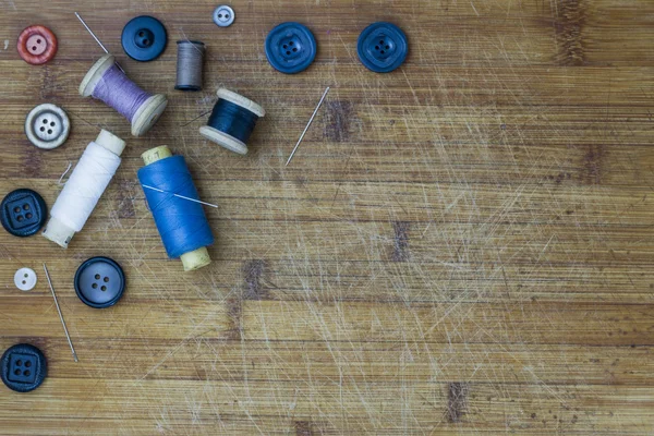 Vintage sewing tools: different colour spools, needles, buttons. Horizontal composition. Wooden background layout with free text space. Top view.