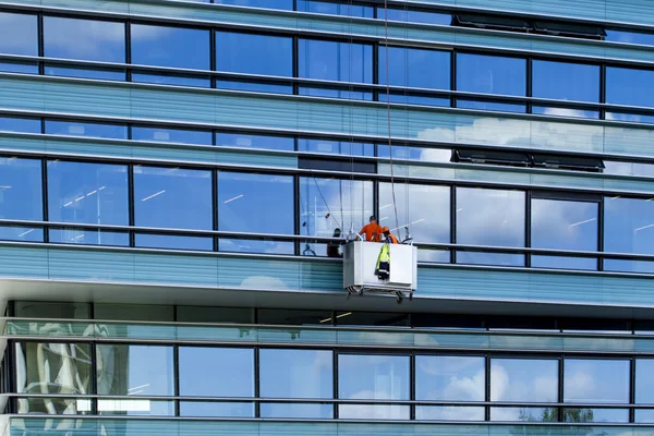 Construction site. Wokers clean the glass wall of new office building. Vilnius, Lithuania - June 29, 2016.