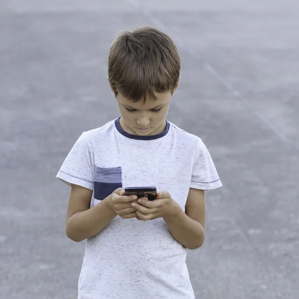 Boy with smartphone texting message, playing game, using apps. Childhood, technology, leisure concept