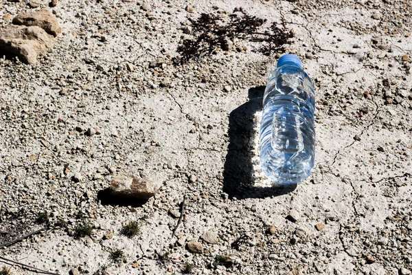 Plastic water bottle on dry and cracked ground. Global warming, ecology concept
