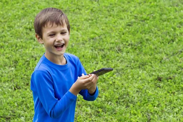 Child with mobile phone outdoor in nature. Childhood, technology, leisure concept