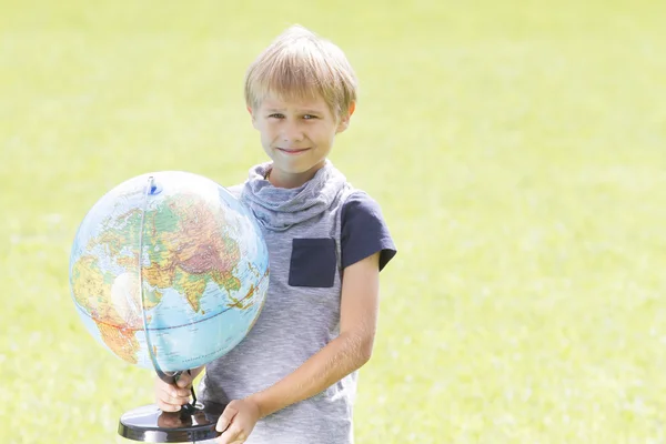 Smiling boy with a globe outside. Education Back to school concept