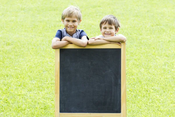 Two little boys standing at the blackboard. Copy space for text.
