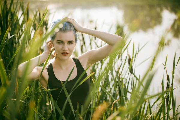 Young beautiful girl with blue hair looks stare predator reed bushes