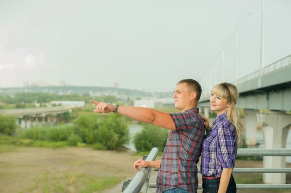 Romantic stroll guy shows girl finger into the distance. loving couple looking far ahead. make plans for future. girl in plaid shirt and shorts. Man in pants and plaid shirt. cloudy summer day.