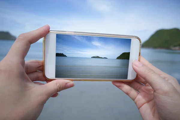 Woman use smart phone take a photo of the sea
