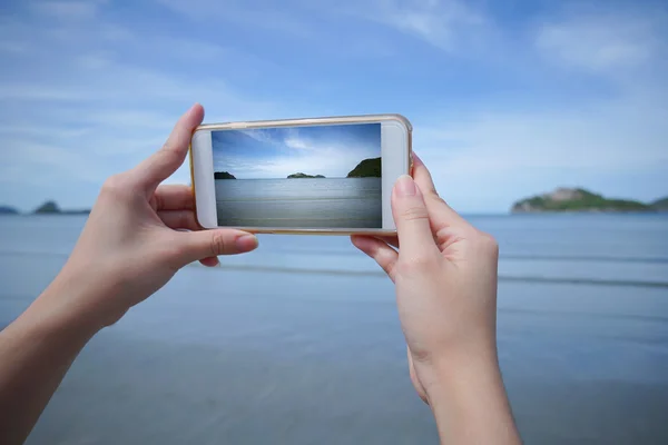Woman use smart phone take a photo of the sea