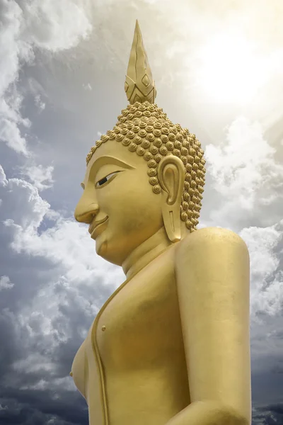 Gold image of Buddha with blue sky and cloud in background,  light effect added , prachuapkhirikhan,thailand,filtered image