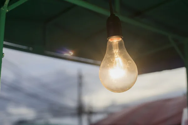 Close up lights bulb hanging on a bar with flare of light bulb ,out door,filtered image,selective focus