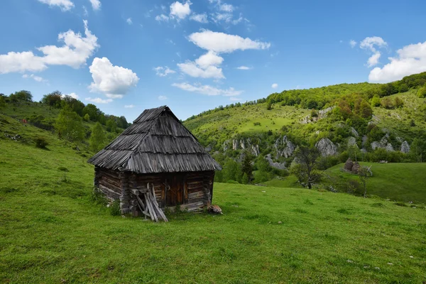 Lonely old wood house on a mountain hill against cloudy sky