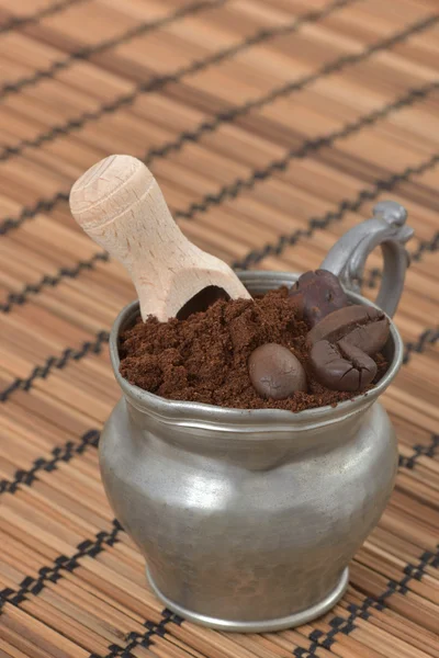 Vintage metal cup with ground and beans coffee on a brown wood background