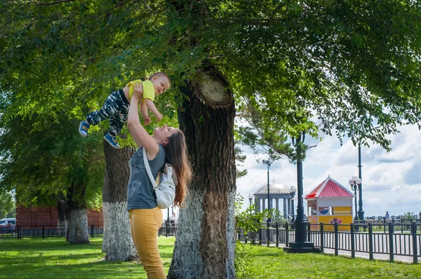Mother and son playing in the Park near the tree on his hands