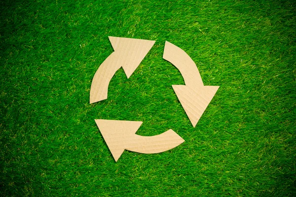 Recycling symbol on green grass background