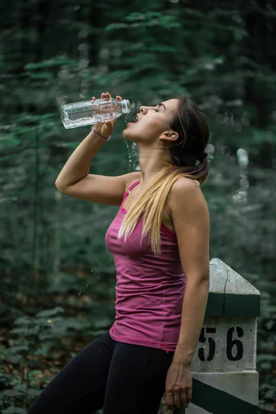 Sporty girl drinks water after running, sport