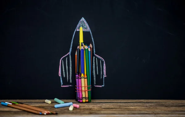 Back to school black background the missile made with pencils, drawing crayons books