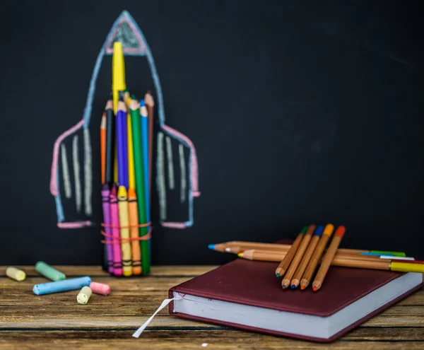 Back to school black background the missile made with pencils, drawing crayons books