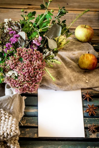 Still life on a wooden Desk with flowers in  vase and apples. Place for text