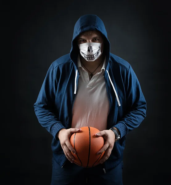 Studio on a black background portrait of guy in mask with basketball