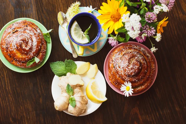 Cup with tea, ginger root and baked goods