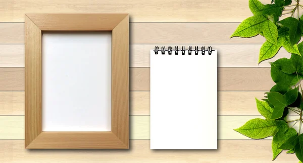 Simple photo frame and white note pad on wood background