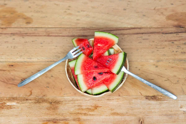 Slices of watermelon on a coconut on the wooden table.