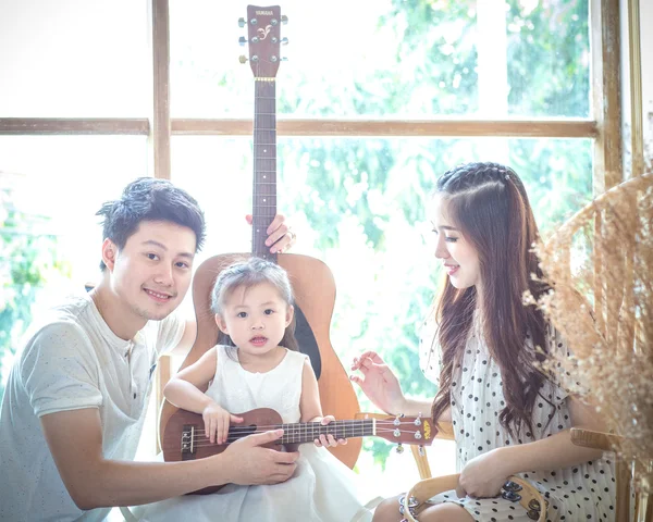 Family making music at home with guitar, Father mother, daughter