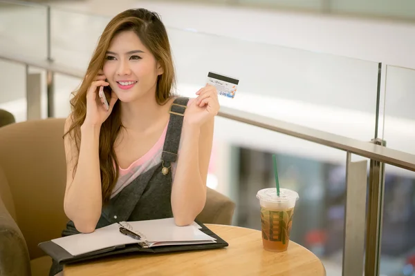 Happy woman shopping online, holding credit card, using ipad com