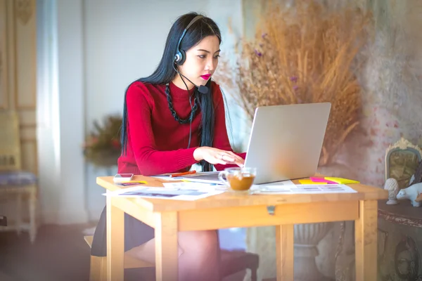 Asian young business woman use laptop sitting at wooden table