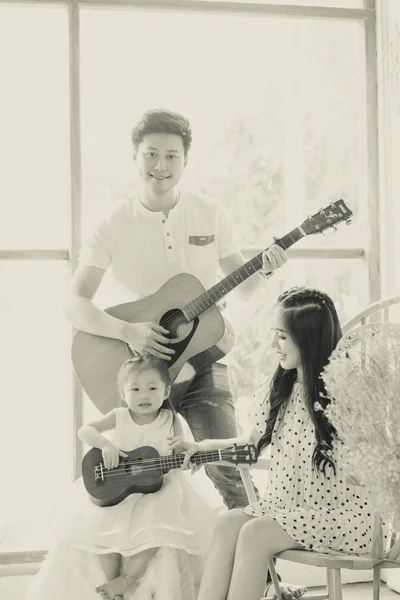 Family making music at home with guitar, Father mother, daughter