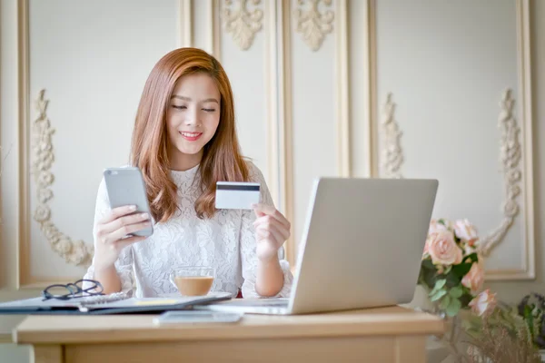 Happy woman shopping online, holding credit card.