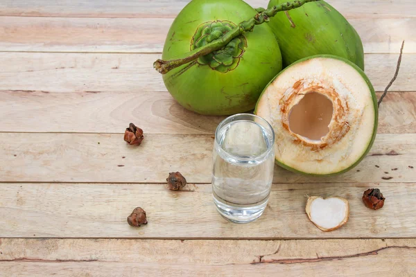Fresh Coconut Water Drink in glass with coconut leaf on wooden  background