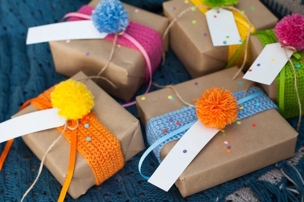 Gifts wrapped in kraft paper lie on a knitted rug.