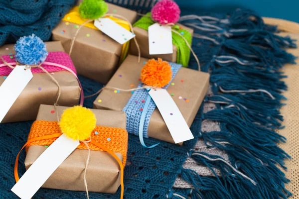 Gifts wrapped in kraft paper lie on a knitted rug.